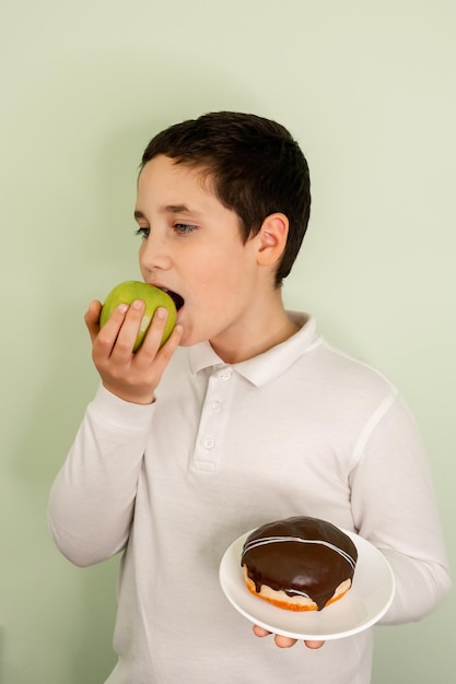 Pretty boy eating an apple while holding cake in other hand