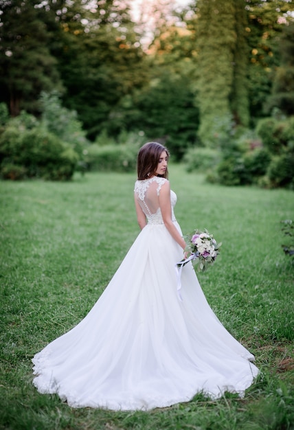 Pretty bride in a white dress stands in the garden