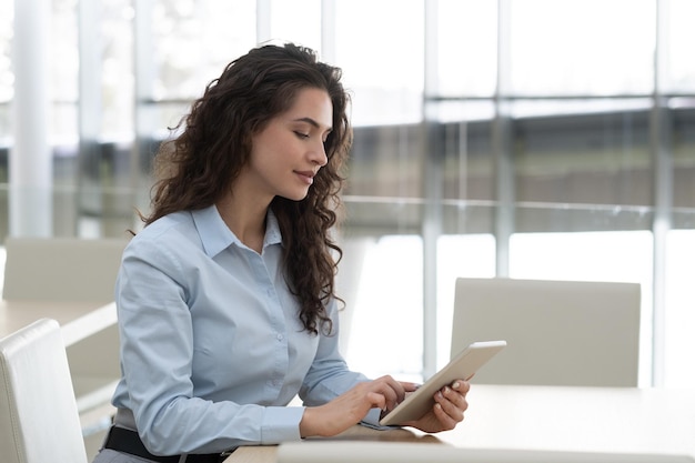 Pretty brunette female manager in formalwear touching screen of tablet