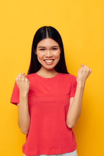 Pretty brunette gestures with her hands in casual clothes copyspace yellow background unaltered