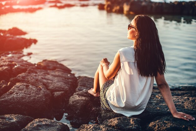 Pretty brunette girl relaxing in the stones