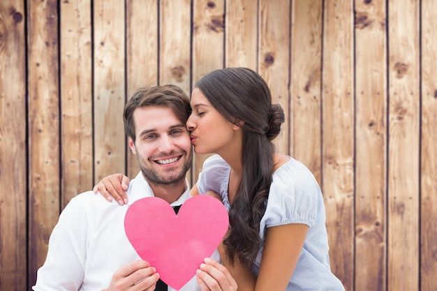 Pretty brunette giving boyfriend a kiss and her heart against wooden planks