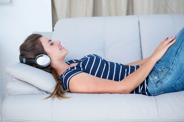 Pretty brunette listening music on couch 