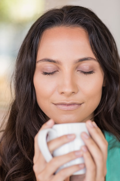 Pretty brunette smelling her coffee