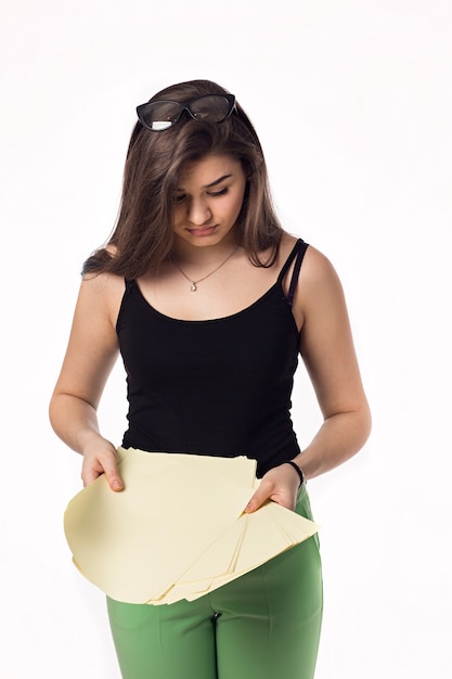 Pretty brunette student girl in green pants with papers