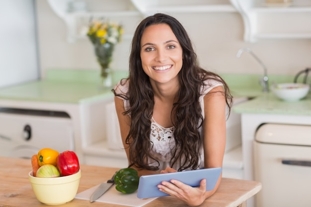 Pretty brunette using tablet pc and preparing salad 