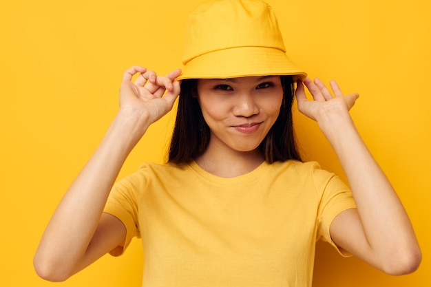 Photo pretty brunette in a yellow t-shirt and hat posing emotions yellow background unaltered. high quality photo