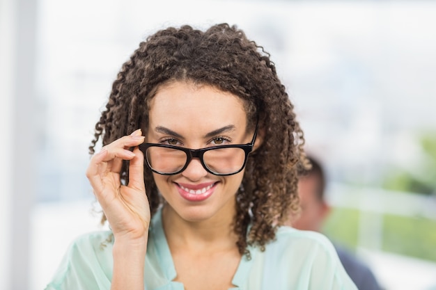 Pretty businesswoman tilting her reading glasses