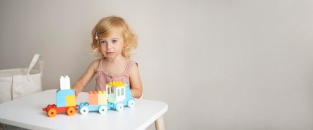 Pretty caucasian 1,2 year old with blond curly hair playing with colourful construction cubes toys