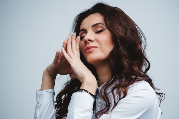 Pretty caucasian brunette woman in a white shirt with blue eyes, long curly hair and fresh skin