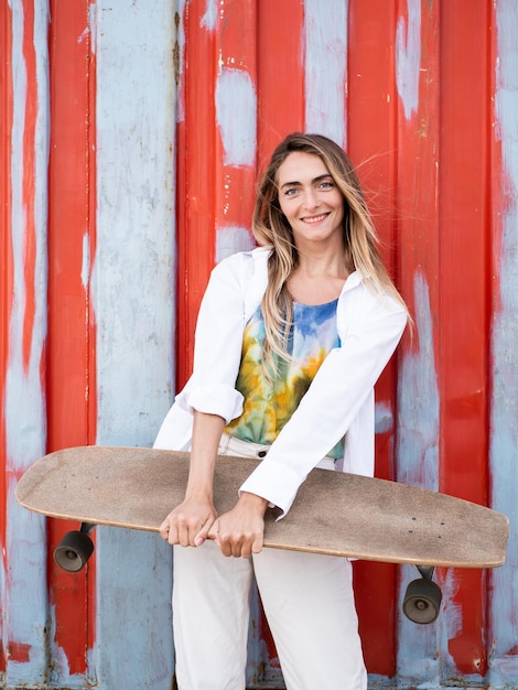 Pretty caucasian skater woman portrait standing at a red background