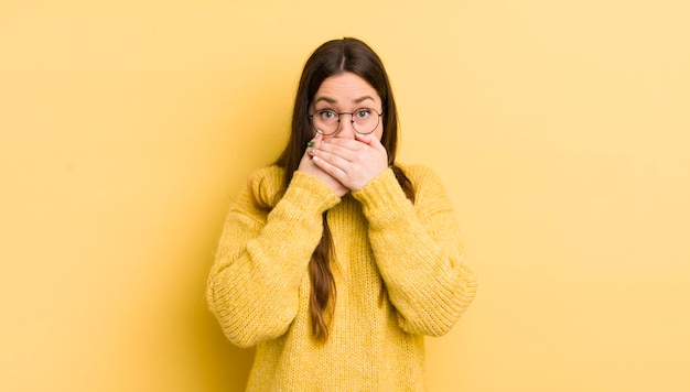 Pretty caucasian woman covering mouth with hands with a shocked surprised expression keeping a secret or saying oops