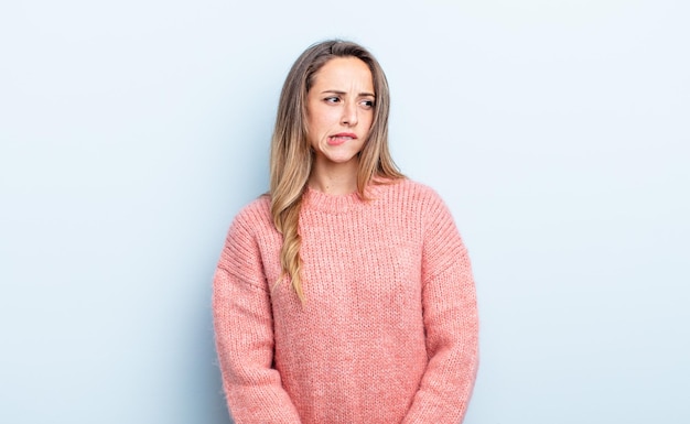 pretty caucasian woman doubting or thinking, biting lip and feeling insecure and nervous, looking to copy space on the side