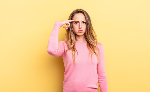 Pretty caucasian woman feeling confused and puzzled, showing you are insane, crazy or out of your mind