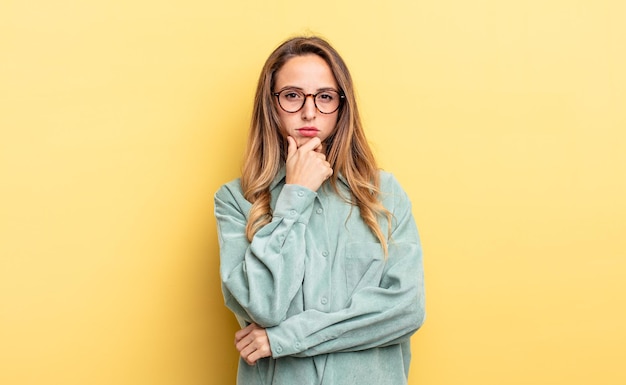 Pretty caucasian woman looking serious, confused, uncertain and thoughtful, doubting among options or choices