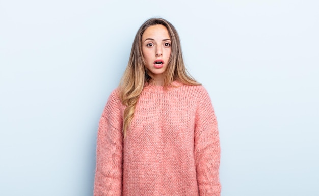 Pretty caucasian woman looking very shocked or surprised, staring with open mouth saying wow