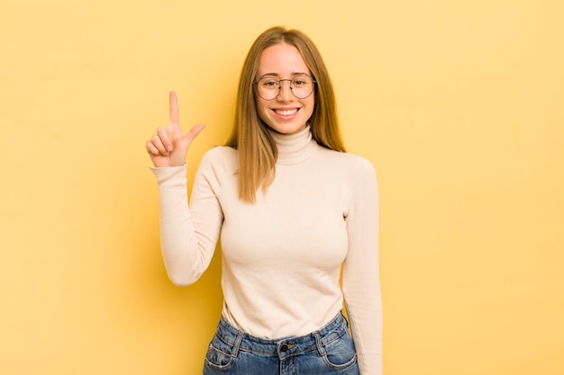 Pretty caucasian woman smiling cheerfully and happily pointing upwards with one hand to copy space