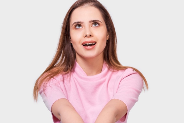 Pretty Caucasian woman student wearing pink blouse smiling broadly looking up with amazed expression isolated over white background