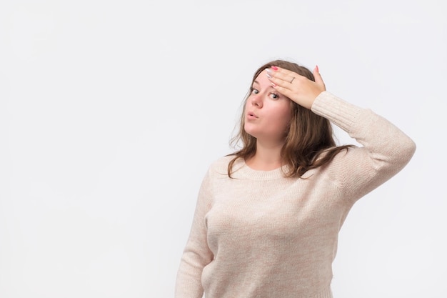 Pretty caucasian woman in sweater wipes the sweat off her forehead