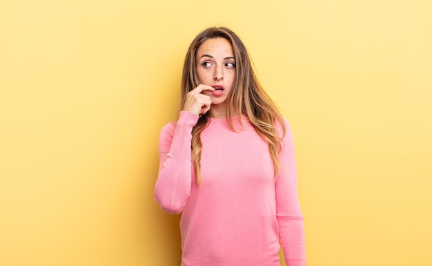 Pretty caucasian woman with surprised, nervous, worried or frightened look, looking to the side towards copy space