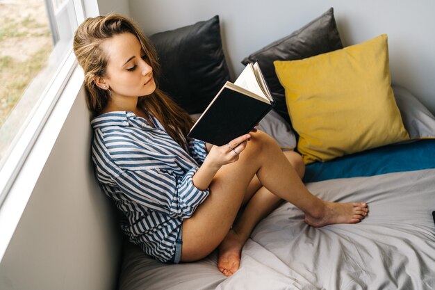 pretty caucasian young female holding a book in her hands while looking at camera