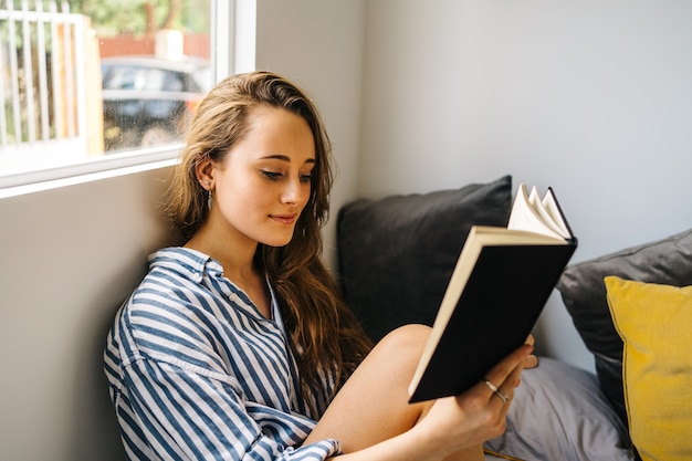 pretty caucasian young female holding a book in her hands while looking at camera