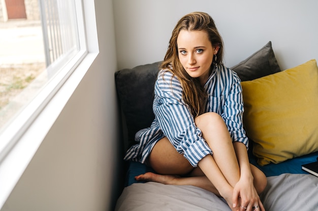 pretty caucasian young female relaxing in her apartment in cozy clothes