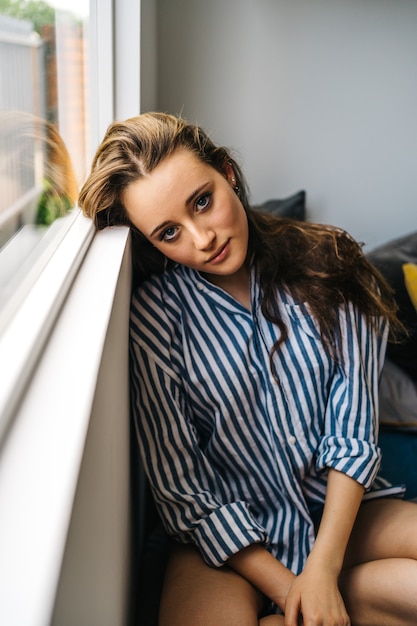 pretty caucasian young female relaxing in her apartment in cozy clothes