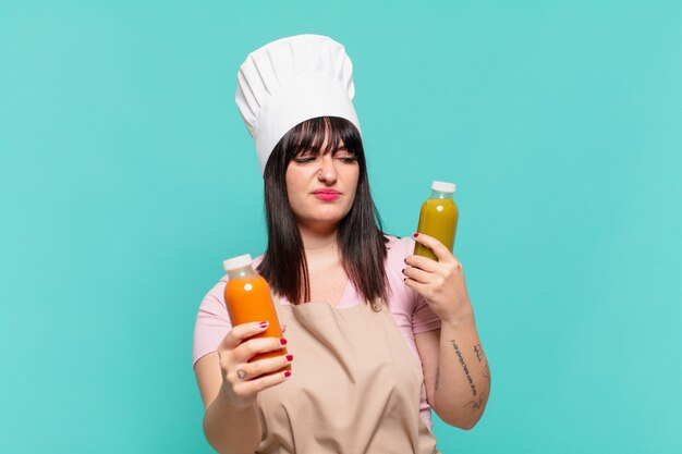 Pretty chef woman doubting or uncertain expression and holding a smoothy