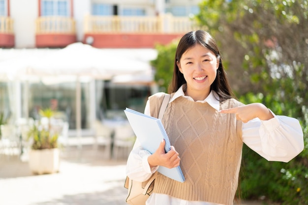 Pretty Chinese student woman at outdoors with surprise facial expression