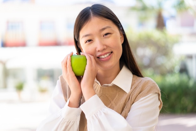 Pretty Chinese woman at outdoors holding an apple