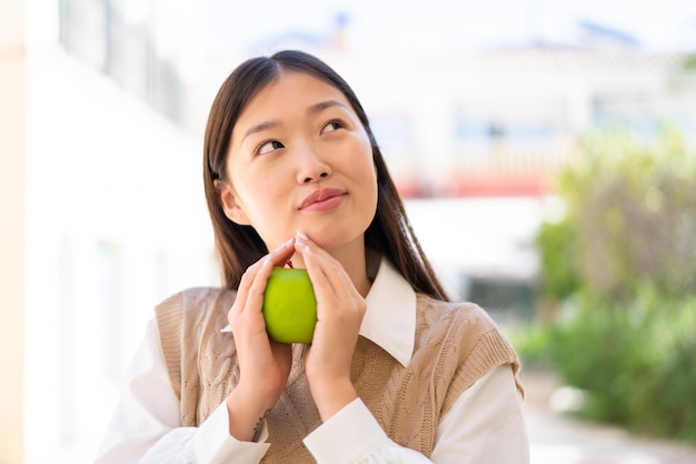 Pretty Chinese woman at outdoors holding an apple