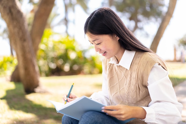 Pretty Chinese woman at outdoors holding a notebook