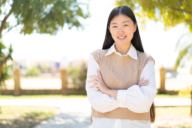 Pretty Chinese woman at outdoors keeping the arms crossed in frontal position