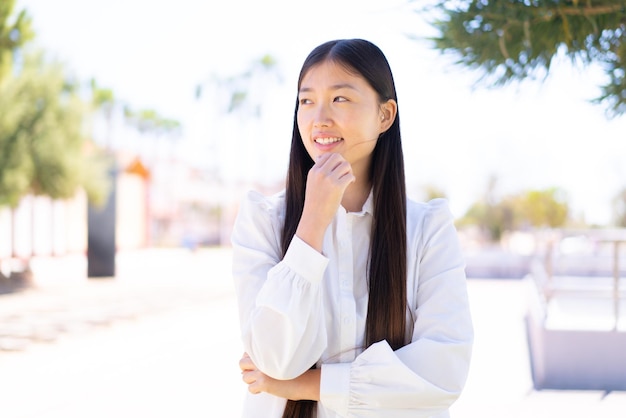 Pretty Chinese woman at outdoors looking to the side