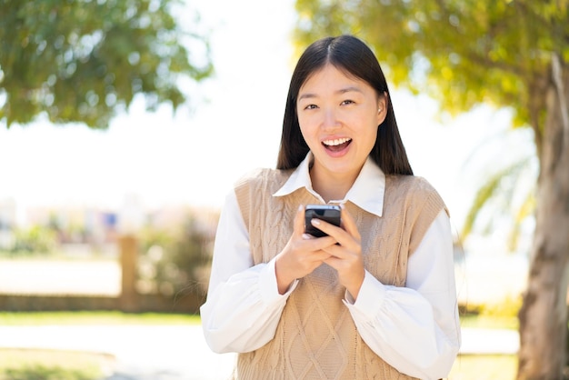 Pretty Chinese woman at outdoors surprised and sending a message