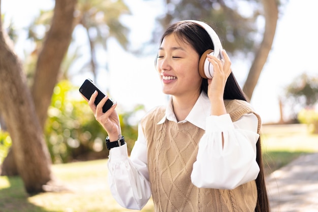 Pretty Chinese woman at outdoors using mobile phone