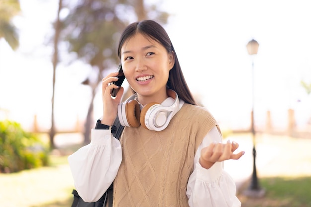 Pretty Chinese woman at outdoors using mobile phone