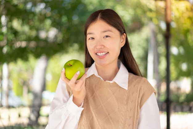 Pretty Chinese woman at outdoors with an apple