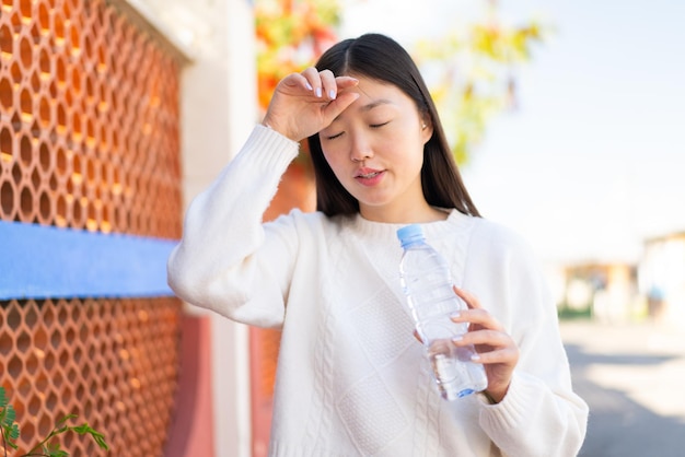 Pretty Chinese woman with a bottle of water at outdoors