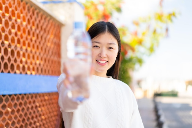 Pretty Chinese woman with a bottle of water at outdoors