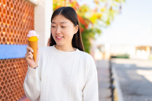 Pretty Chinese woman with a cornet ice cream at outdoors with happy expression