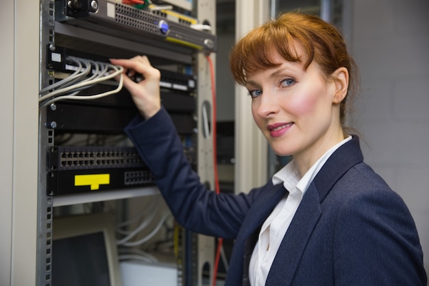 Pretty computer technician smiling at camePretty computer technician smiling at camera while fixing 