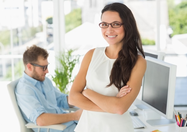 Pretty designer smiling at camera leaning on desk