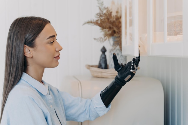 Pretty disabled girl opens kitchen cupboard by bionic prosthetic arm Modern prosthesis advertising