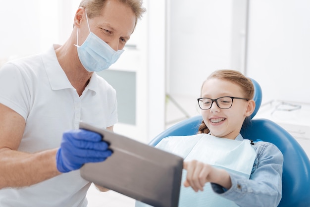 Pretty enthusiastic teenage girl listening a lecture about the procedure she undergoing and asking her doctor a lot of questions