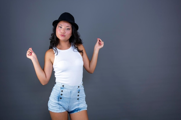 Pretty ethnic asian girl posing in tank top shorts and hat