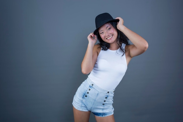 Pretty ethnic asian girl posing in tank top shorts and hat