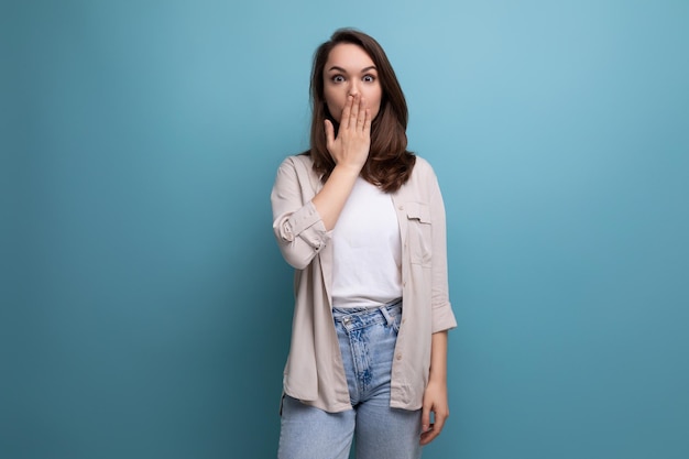 Pretty european brunette young woman in a stylish look on a blue background with copy space