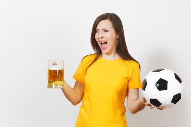 Pretty European young sad upset woman, football fan or player in yellow uniform holds pint mug of beer, worries about losing team isolated on white background. Sport, play football, lifestyle concept.